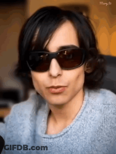 Man In Sunglasses And Blue Sweater Looking At Camera GIF