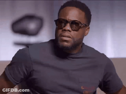 Man In Sunglasses And Grey T-Shirt Looking At Camera GIF