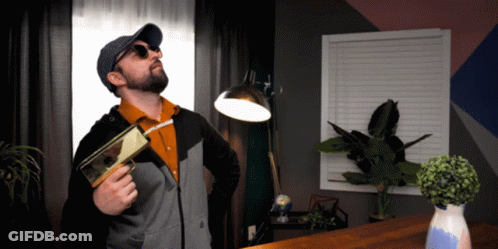 Man In Sunglasses And Hat Holding Book And Lamp GIF