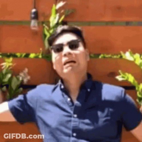 Man In Sunglasses And Hat Making Funny Face In Front Of Wooden Wall GIF