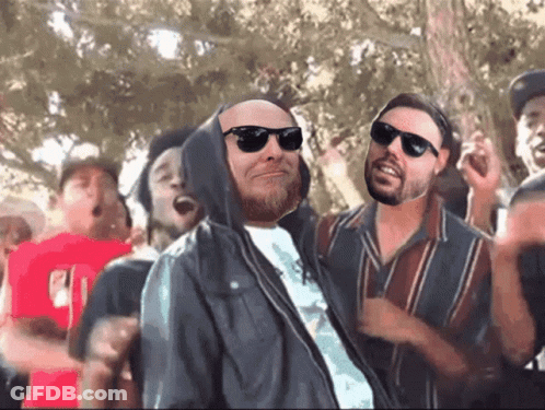 Man In Sunglasses And Hooded Jacket In Crowd GIF