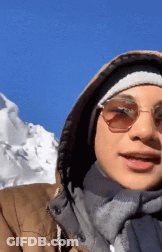 Man In Sunglasses And Hooded Jacket In Front Of Snowy Mountain GIF
