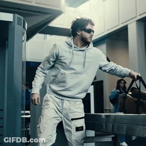 Man In Sunglasses And Hoodie Carrying Suitcase GIF