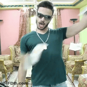 Man In Sunglasses And Necklace With Arms Outstretched In Living Room GIF