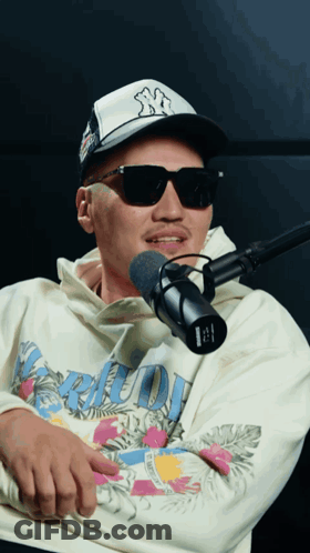 Man In Sunglasses And NY Hat Talking Into Microphone GIF
