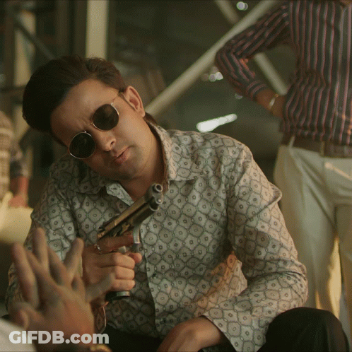 Man In Sunglasses And Patterned Shirt Holding Gun GIF