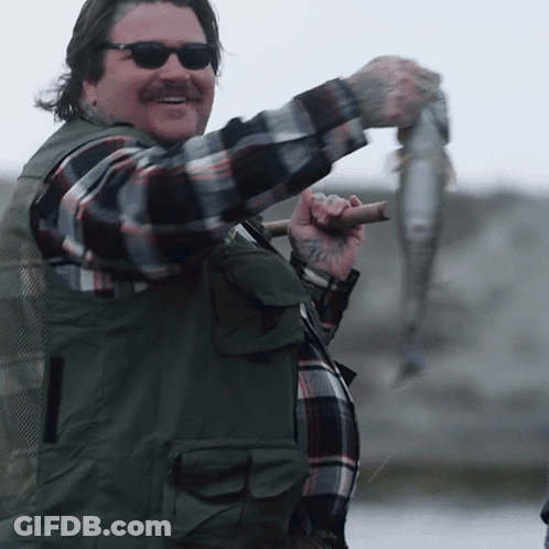 Man In Sunglasses And Plaid Shirt Holding Fish On Stick GIF