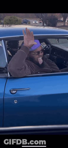 Man In Sunglasses And Purple Hat Waving From Blue Car GIF
