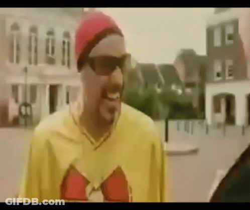Man In Sunglasses And Red Hat Standing In Front Of Building GIF