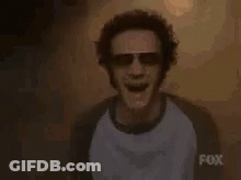 Man In Sunglasses And T-Shirt In Front Of High Sign GIF