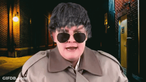 Man In Sunglasses And Trench Coat At Brick Wall GIF