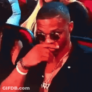 Man In Sunglasses Covering Mouth In Crowd GIF