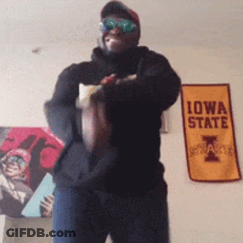 Man In Sunglasses Holding Football In Front Of Iowa State Sign GIF