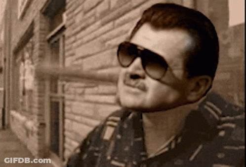 Man In Sunglasses In Front Of Brick Building GIF