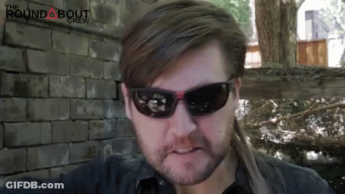 Man In Sunglasses In Front Of Brick Wall With Roundabout Crew GIF