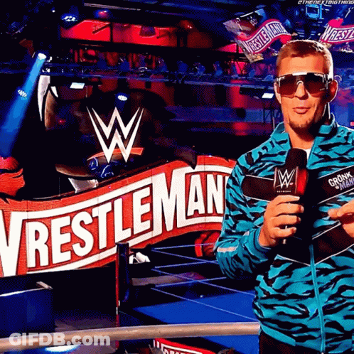 Man In Sunglasses In Front Of Wrestlemania Sign GIF