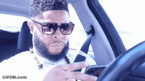Man In Sunglasses Looking At Phone While Driving GIF
