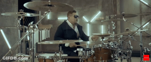 Man In Sunglasses Playing Drums In Front Of Drums Sign GIF