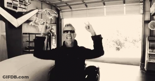 Man In Sunglasses Sitting In Garage Arms Outstretched GIF