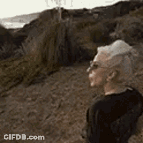 Man In Sunglasses Standing On Dirt Path Looking At Ocean GIF
