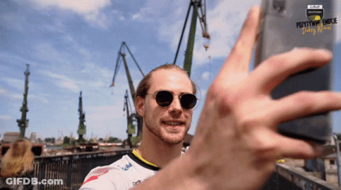 Man In Sunglasses Taking Selfie In Front Of Pottymouth Dunk Sign GIF