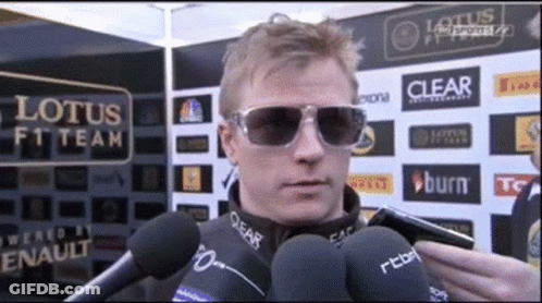 Man In Sunglasses Talking Into Microphone At Lotus F1 Sign GIF