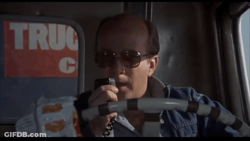 Man In Sunglasses Talking On Phone In Front Of Truck C Sign GIF