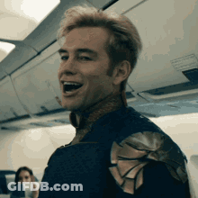 Man In Superhero Costume Sitting On Airplane GIF