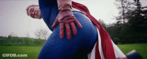 Man In Superhero Costume Standing In Grassy Field GIF