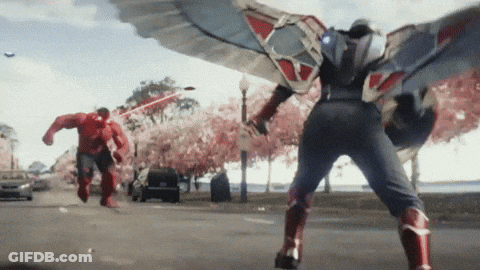 Man In Superhero Costume Walking Next To Red Hulk GIF