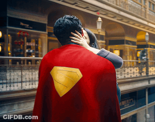 Man In Superman Cape Hugged By Woman GIF