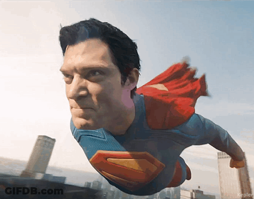 Man In Superman Costume Flying Over City GIF