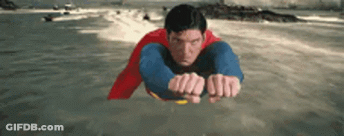 Man In Superman Costume Flying Over Water GIF