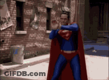 Man In Superman Costume In Front Of Brick Building GIF