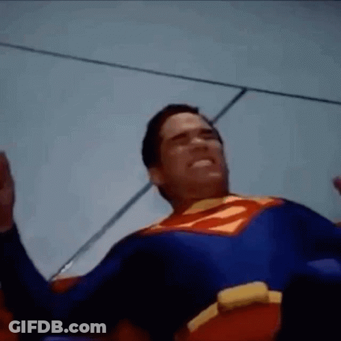 Man In Superman Costume Laying On Ground With Hands Up GIF