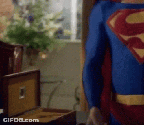 Man In Superman Costume Standing Next To Cigar Box GIF