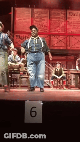 Man In Suspenders Dancing On Stage With Number 6 Sign GIF