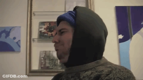Man In Sweater And Hooded Jacket In Front Of Framed Picture GIF