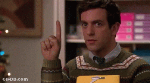 Man In Sweater And Tie Holding Book Pointing Up GIF