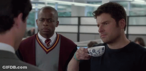 Man In Sweater And Tie Holding Coffee GIF