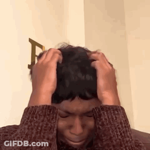 Man In Sweater Holding Head In Pain GIF