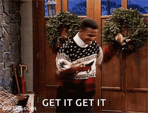 Man In Sweater Holding Wreath And Gun GIF