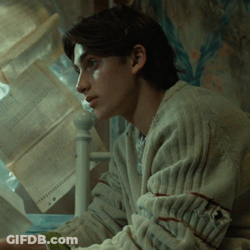 Man In Sweater In Front Of Paper Stack GIF