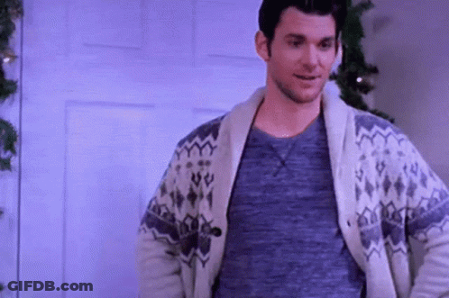 Man In Sweater Smiling By Christmas Tree GIF