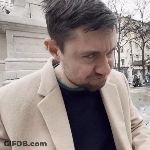 Man In Tan Coat And Black Sweater Making A Face GIF
