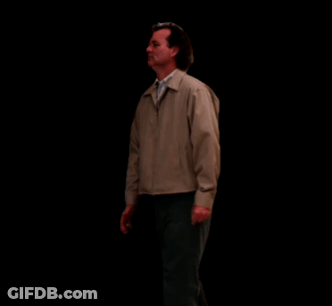 Man In Tan Jacket And Black Pants Walking In Dark Room GIF