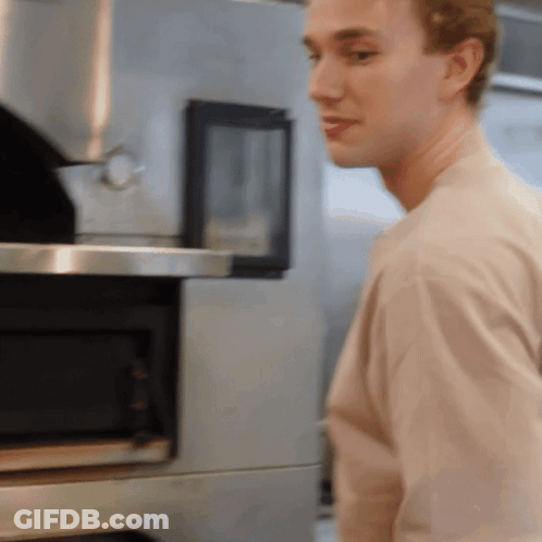 Man In Tan Shirt In Front Of Microwave GIF