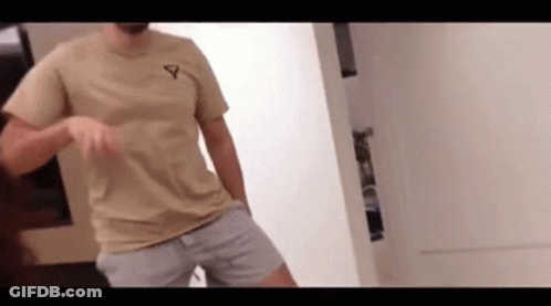 Man In Tan T-Shirt And Shorts Standing In Room GIF