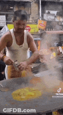 Man In Tank Top Cooking On Stove GIF