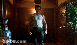 Man In Tank Top Holding Claws Out In Hallway GIF